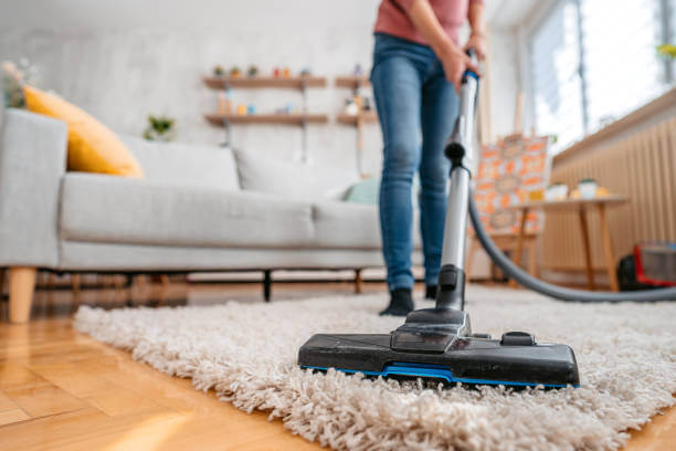 A man is cleaning carpet with vaccum.